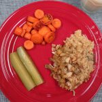 Four grain pilaf on a dinner plate with roasted carrots and dill pickles
