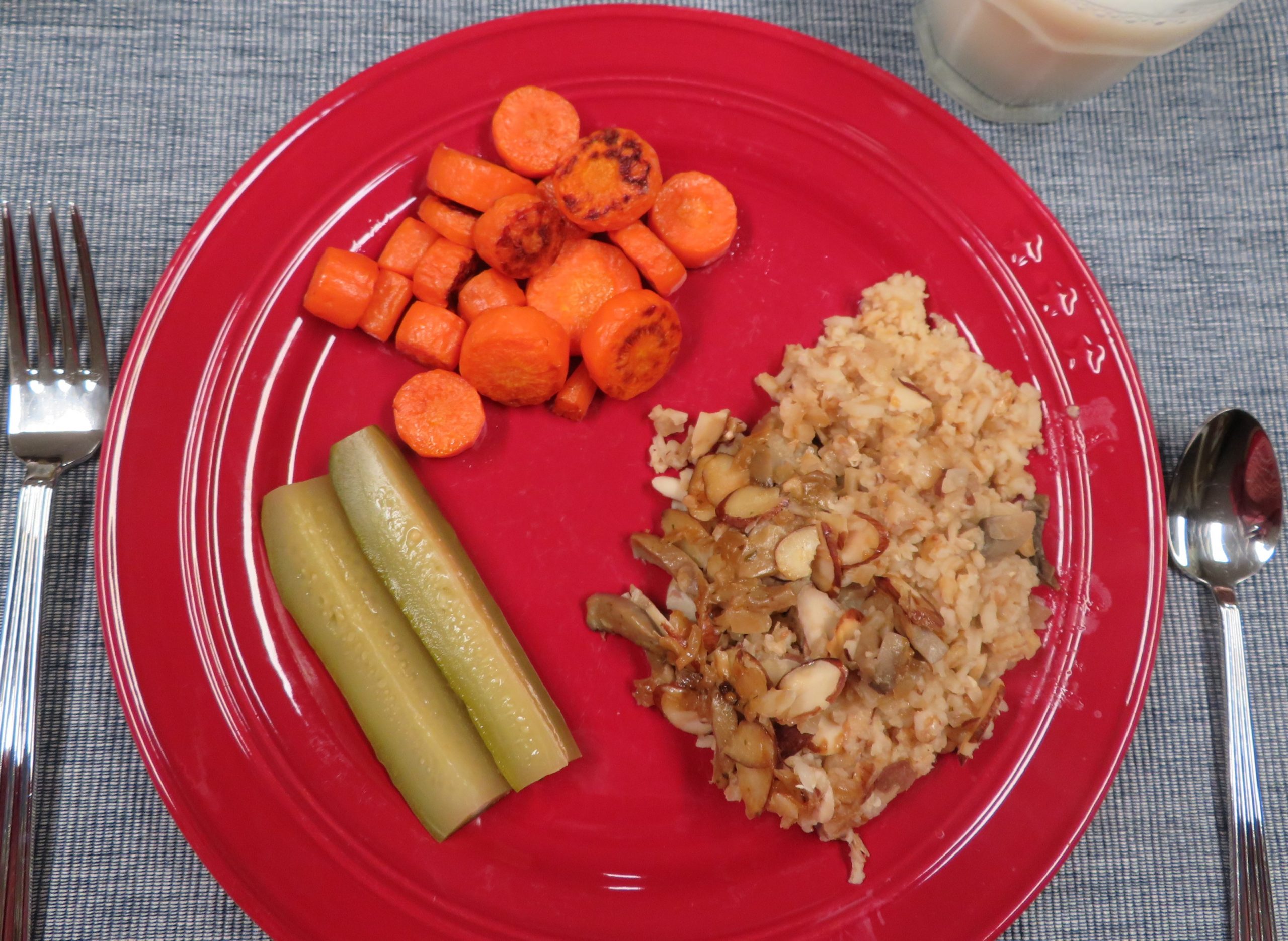Four grain pilaf on a dinner plate with roasted carrots and dill pickles