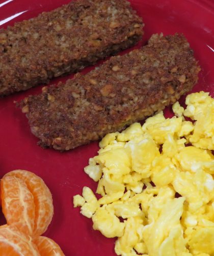 Walnut and oat sausage on a plate with scrambled eggs and oranges