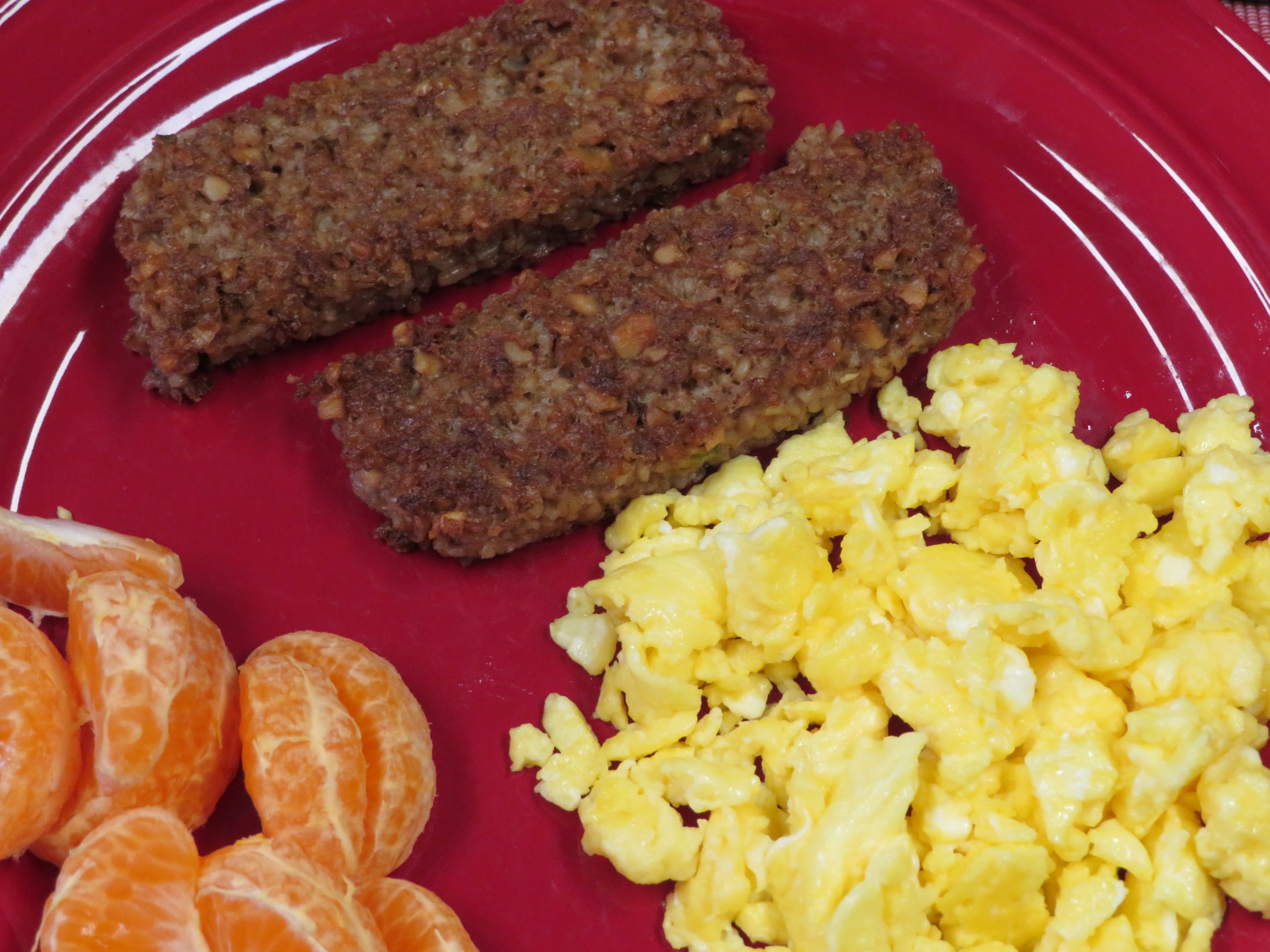 Walnut and oat sausage on a plate with scrambled eggs and oranges