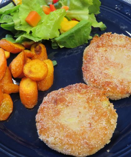 Artichoke cakes on a blue plate with roasted carrots and tossed salad