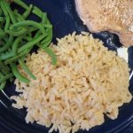 Tex Mex Seasoned Rice on a plate with green beans and a pork chop