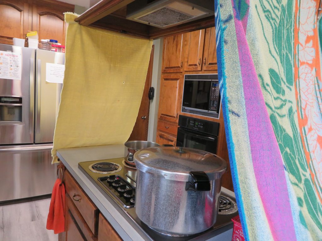 Towels clamped to overhead vent on either end of the stove top island.