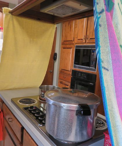 Towels clamped to overhead vent on either end of the stove top island.