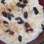 Sweetened rice, raisins, and cinnamon in a red bowl.