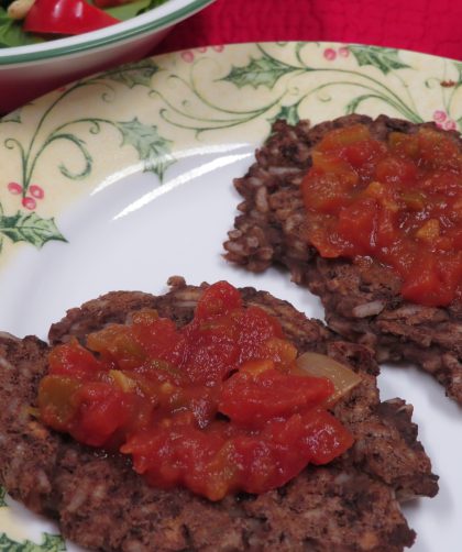 Two Bean and Rice Cakes with salsa on them sitting on a plate