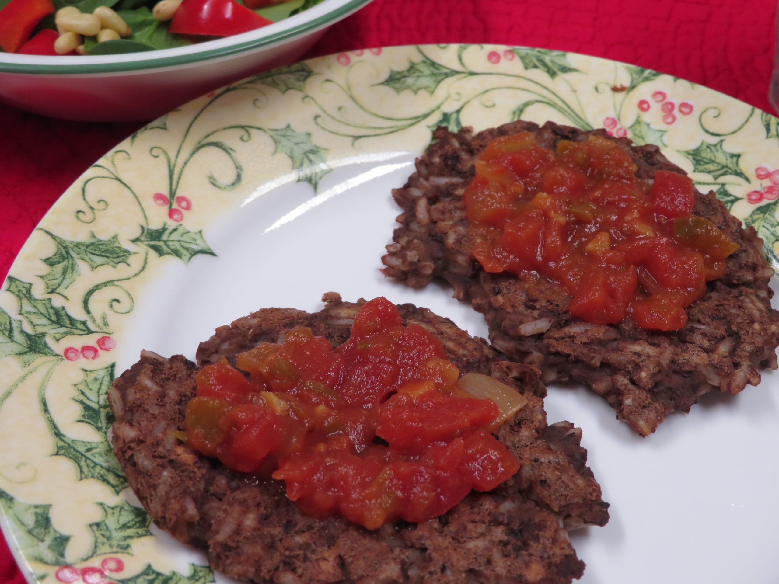 Two Bean and Rice Cakes with salsa on them sitting on a plate