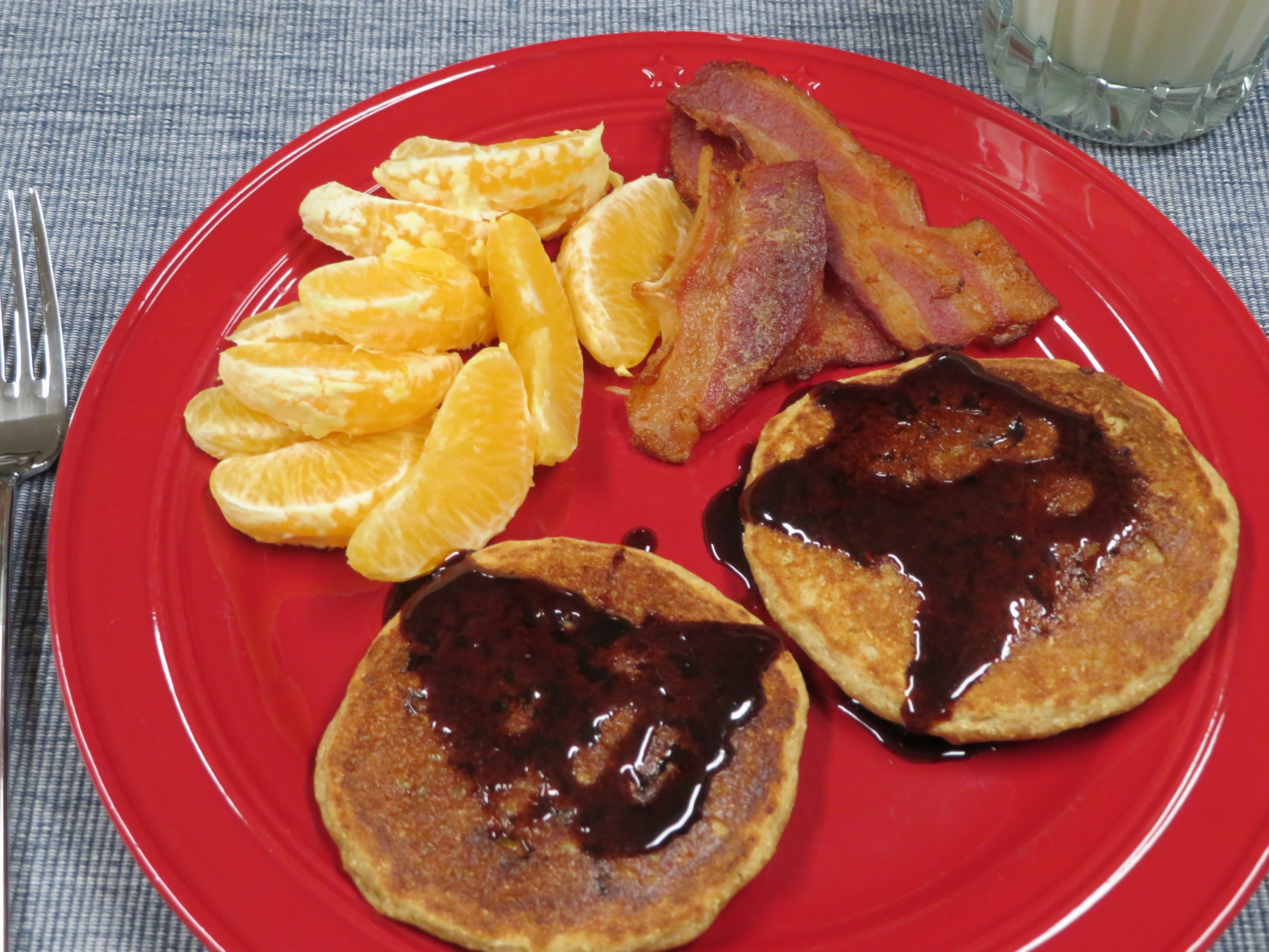 Multigrain Pancakes on a plate with bacon and orange slices