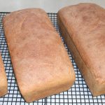Three loaves of whole wheat bread on cooling racks