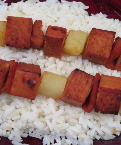 Two Turkey Kabob skewers laying on a bed of rice
