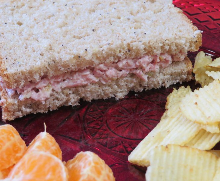 Spam Salad sandwich on a plate with potato chips and orange sections